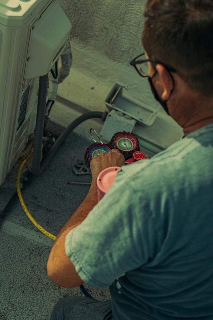 Your Local HVAC Contractor Professional technician repairing an outdoor air conditioning unit with gauges and tools.