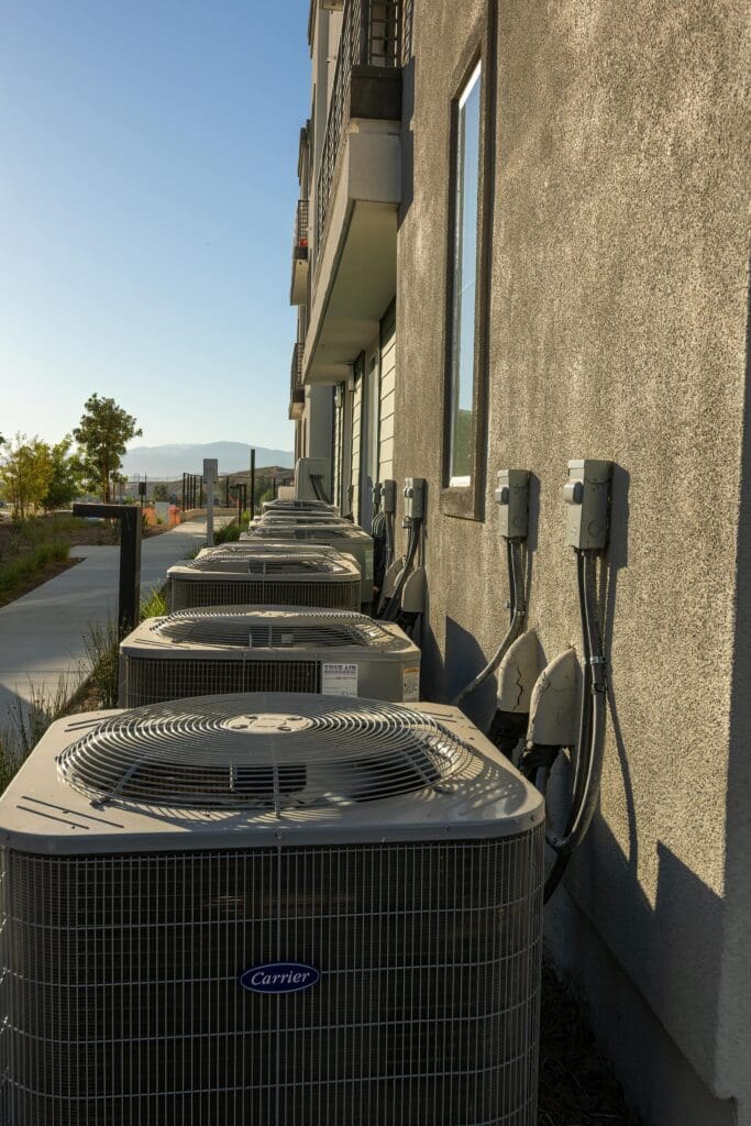 Mini Split Maintenance  air conditioning units on a city apartment exterior with a sidewalk view.