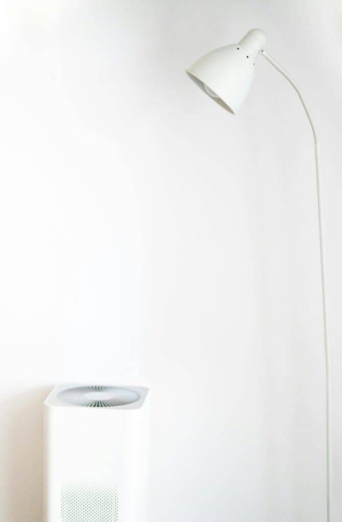 A minimalist room featuring a white floor lamp and air purifier against a blank wall.