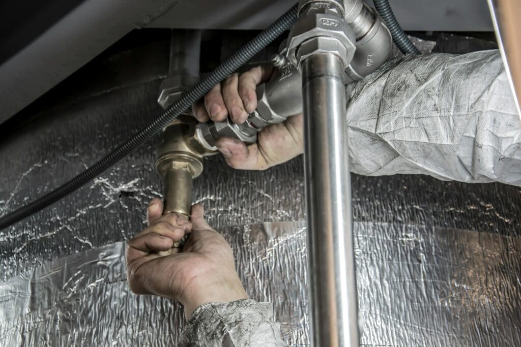 Choosing a Plumber: close-up of skilled hands installing steel pipes indoors.
