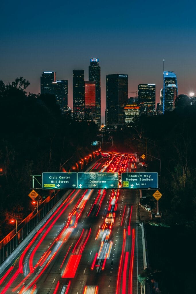 Dynamic Los Angeles skyline at night with light trails on the freeway showcasing urban energy.